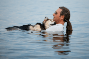 John Unger faz relaxar nas águas mornas do Lago Superior seu cão, Schoep, afetado por dores fortíssimas causadas por artrite e um câncer no quadril: a foto tornou-se viral, a história dos dois rodou o mundo -- e agora, aos 20 anos, Schoep morreu (Foto: Hannah Stonehouse Hudson)