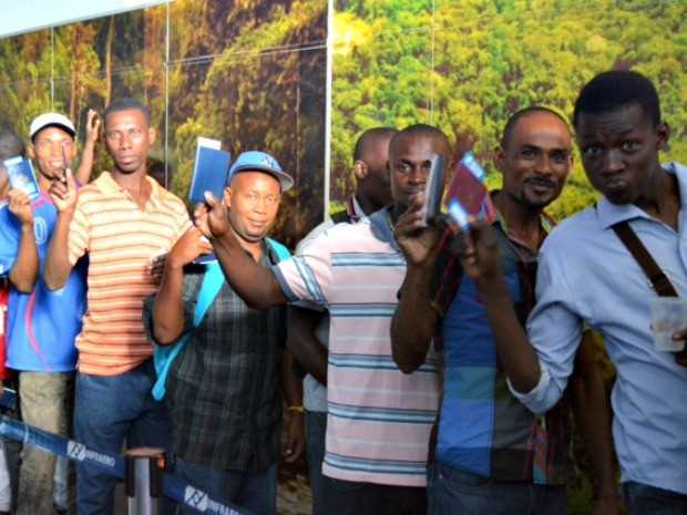 Haitianos comemoram na fila de embarque no aeroporto de Rio Branco (Foto: Yuri Marcel/G1)