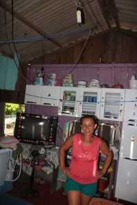 Dona Raimundo mostra sua casa com apenas uma lâmpada, uma geladeira e uma televisão.