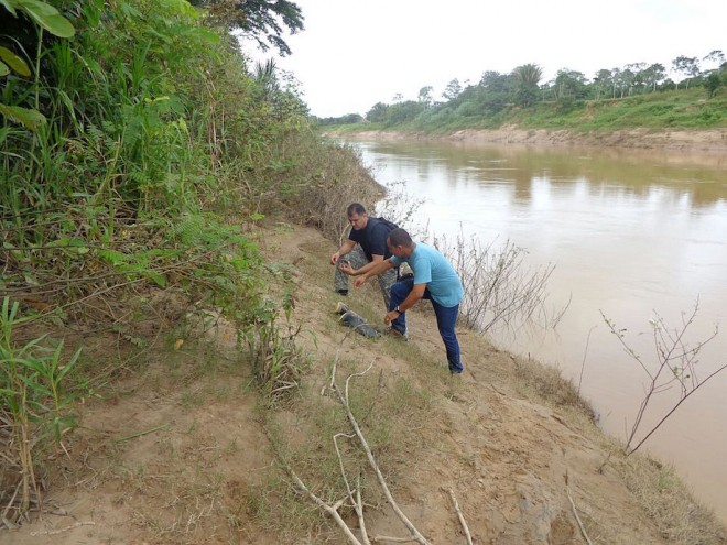 Momento em que os investigadores encontram as botas e o celular da vítima na beira do rio.
