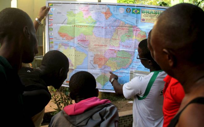 A foto escolhida para ilustrar o livro foi a que mostra refugiados haitianos apontando em um mapa do Brasil /Foto: Odair Leal